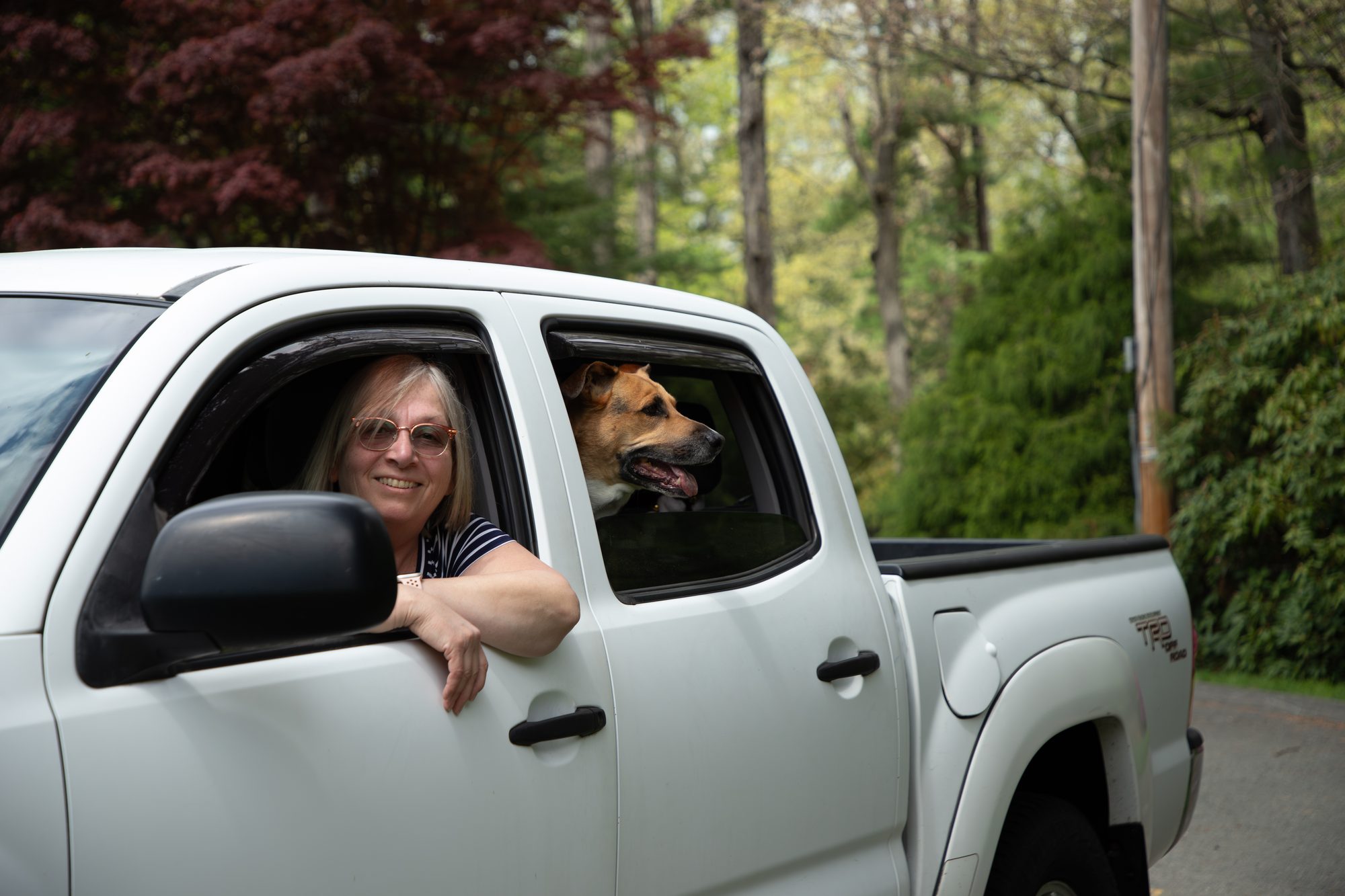 Mama Sue leaning out the truck window, Norbert in the back seat surrounded by trees